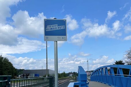 Zusatzschild "So geht Klimaschutz" an der neuen Geh- und Radwegebrücke Wülfingstraße